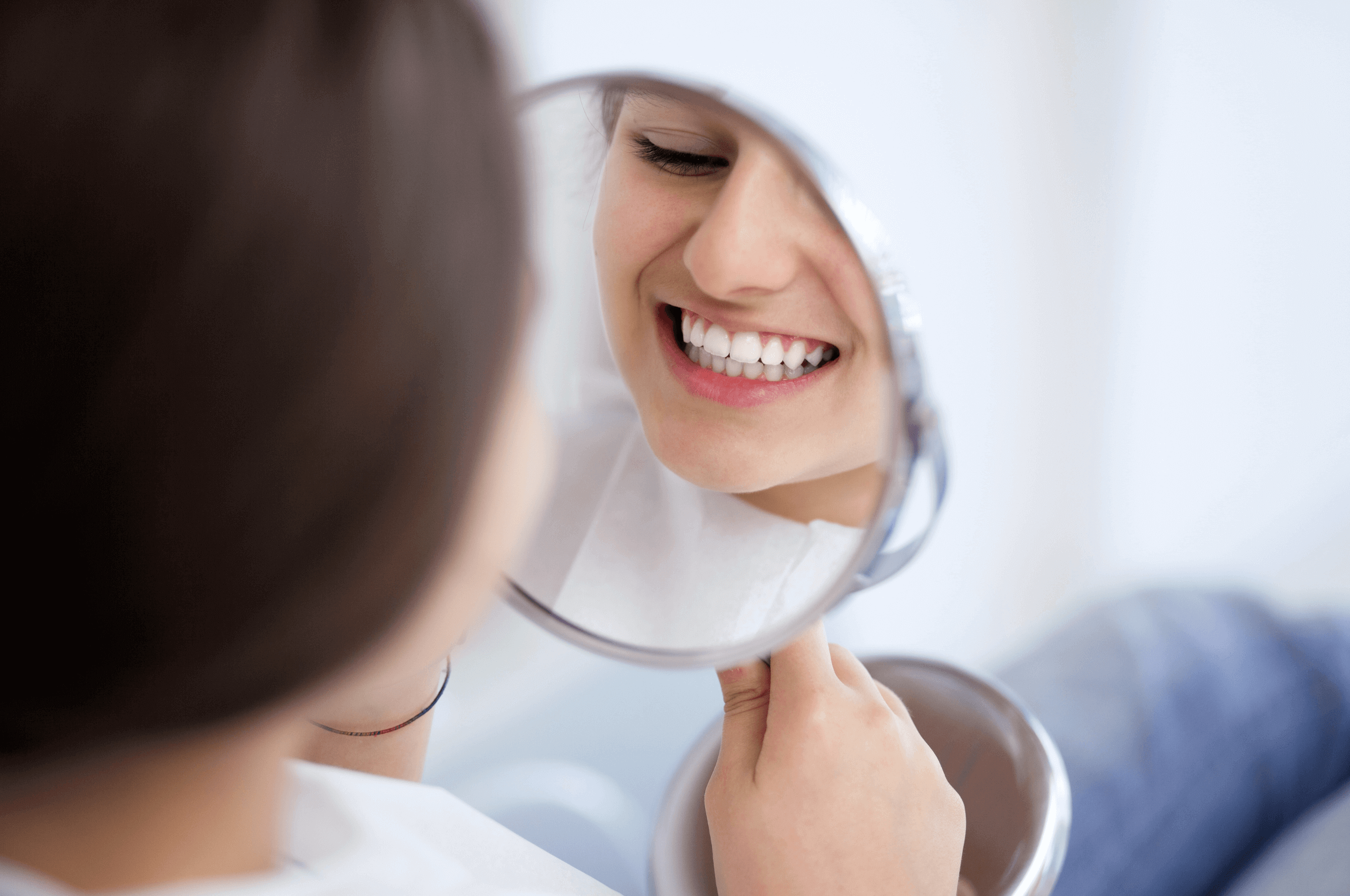Woman smiling in the mirror with dental implants in Nottingham