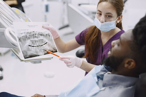 A dentist reviewing a panoramic dental X-ray with a patient during an implant consultation.