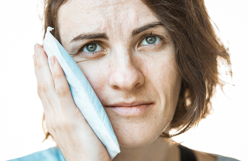 A person using an ice pack to help with swelling after dental implant surgery.