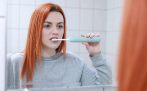 A person using a soft-bristle brush to maintain oral hygiene after dental implant surgery.