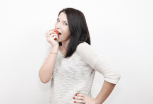 A person biting into an apple after replacing dentures with implants.