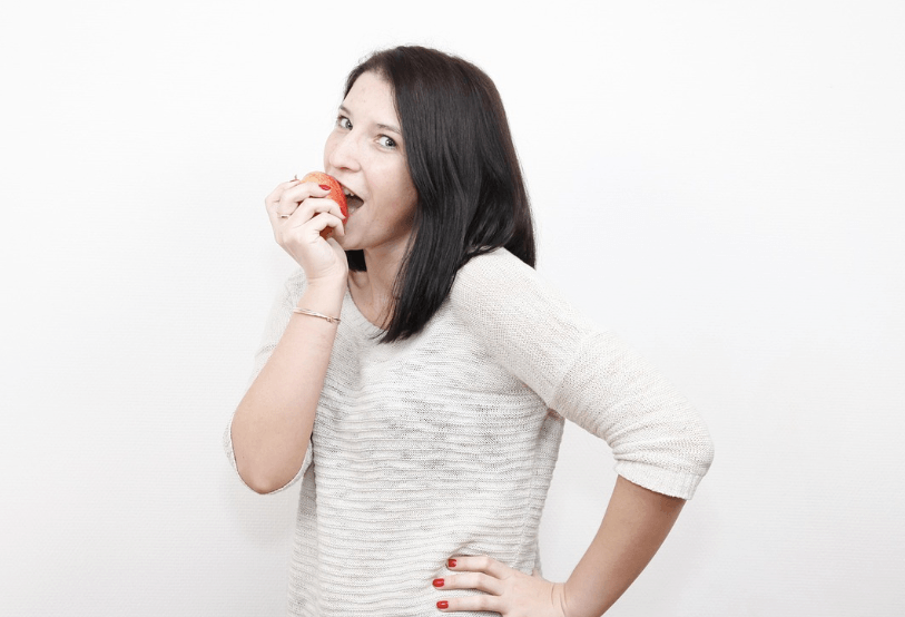 A person biting into an apple after replacing dentures with implants.