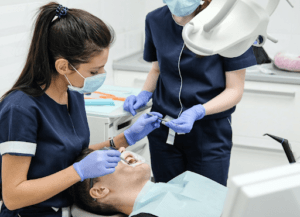 Two dentists working on a person’s veneers.