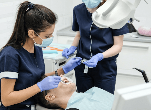 Two dentists working on a person’s veneers. 