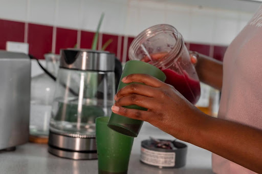 A person pouring a protein smoothie into a cup, a convenient way to maintain nutrition after dental implant surgery.