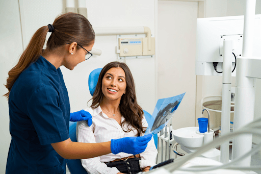 A dental hygienist reviews an X-ray with a patient during a routine implant checkup appointment.
